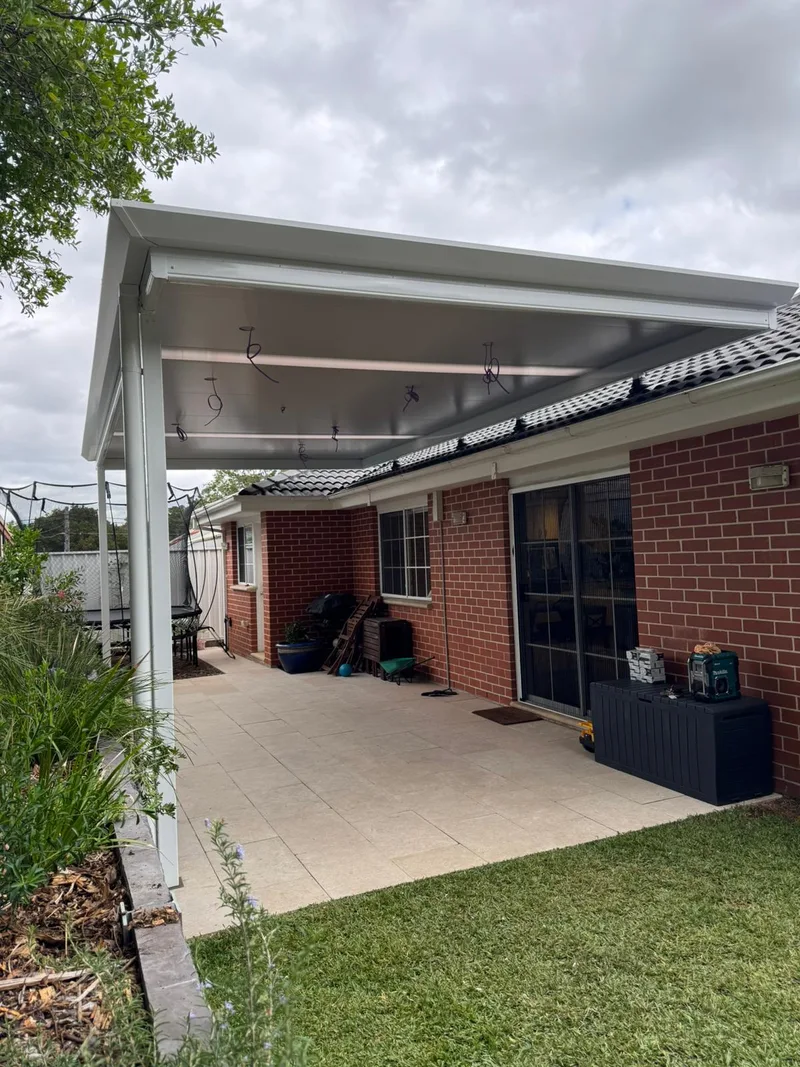 Flyover patio over a paved alfresco beside a brick home — Narellan, NSW