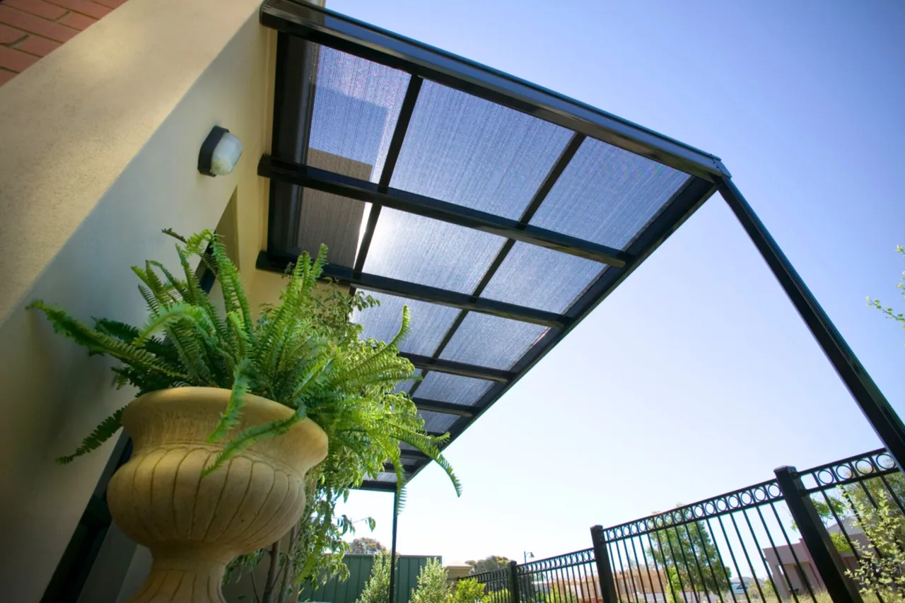Cantilevered polycarbonate pergola sheltering an entry with a fern garden — Penrith, NSW